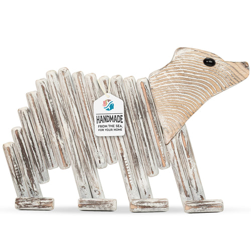 A rustic, handcrafted wooden polar bear figurine with a distressed white and natural wood finish, featuring a small black bead eye on its head and a central 'Handmade from the Sea' label.